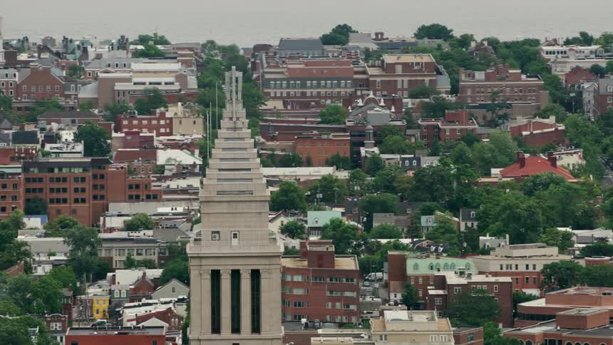 Tower with several antenna looms over town with tree lined avenues