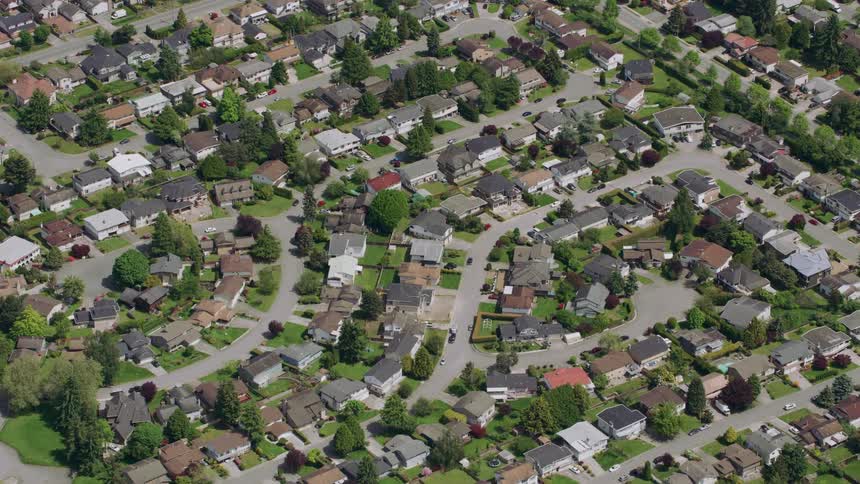 Traffic moves on the streets of a busy suburban neighborhood with houses close together