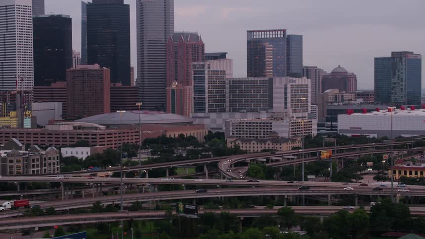 Traffic moves on highways around a big city with tall buildings on the skyline surrounded by suburbs