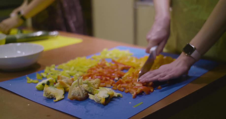 A woman slices and chops peppers on a cutting board