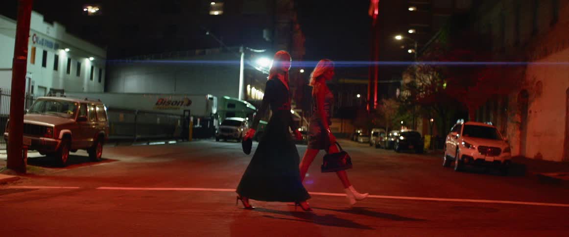 Two women cross a city street at night