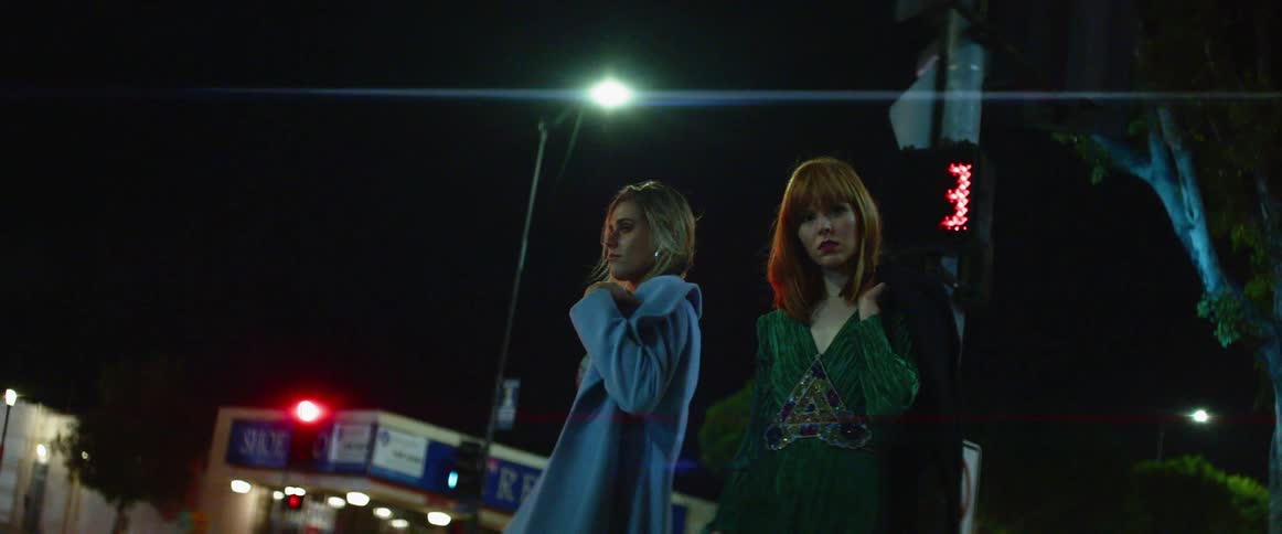 Two women stand on the city street at night