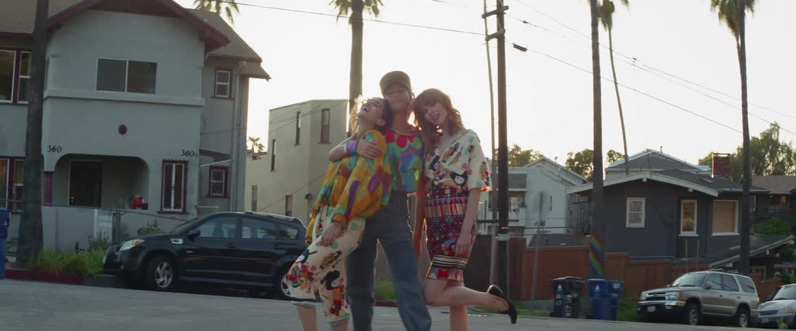 Three women pose on a city sidewalk at sunset