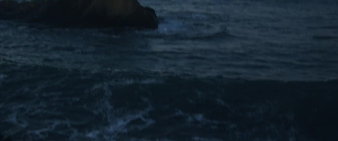 An ocean wave crashing into a rock on a beach at sunset