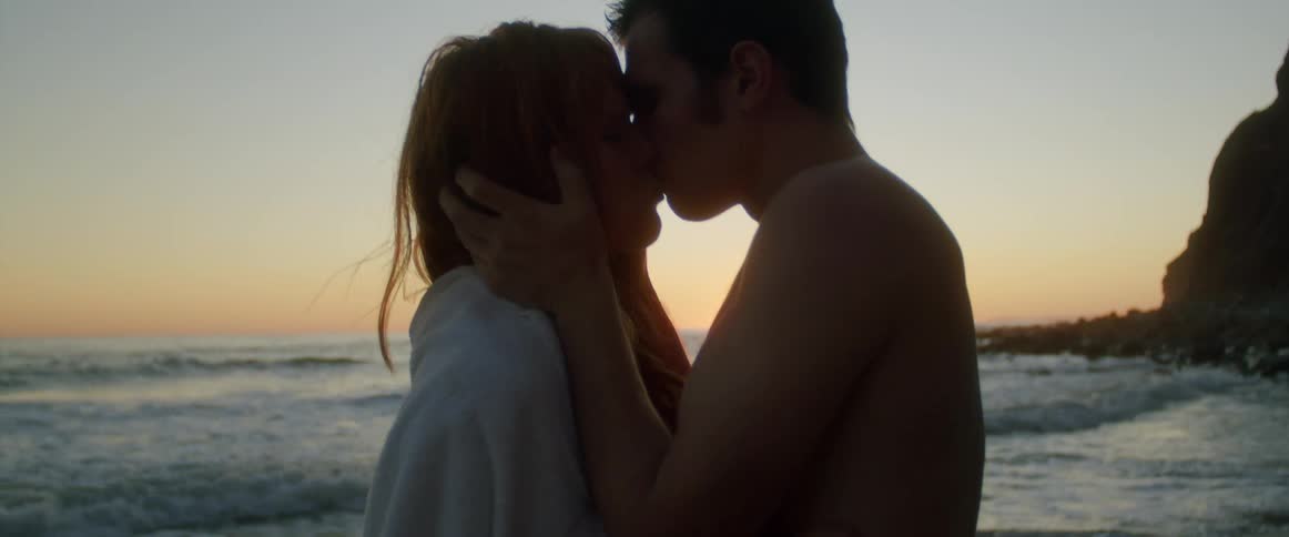 A man and woman kissing on a beach