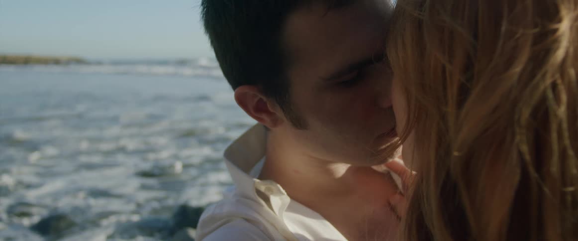 Young couple passionately kiss on the beach at sunset