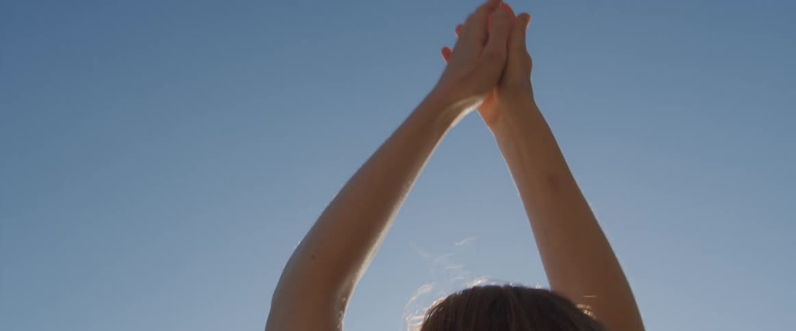 Young woman lifts her arms up and down on the beach