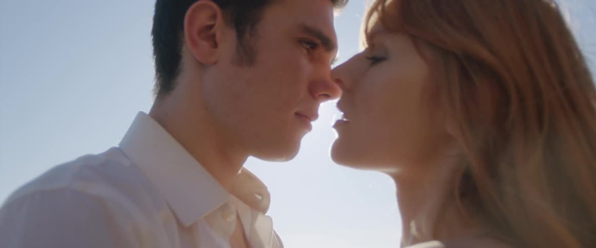A man and woman stand close to each and embrace romantically on the beach