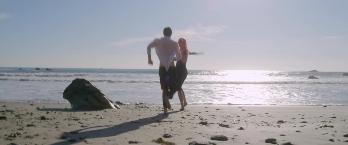 A man and woman are running on the beach