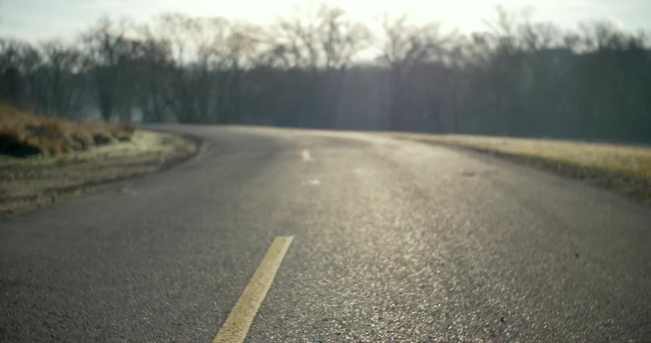 A curved street near a wooded area