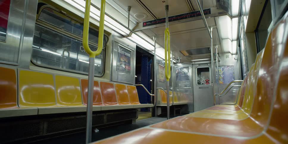 An empty train car with lights on sits in a subway station