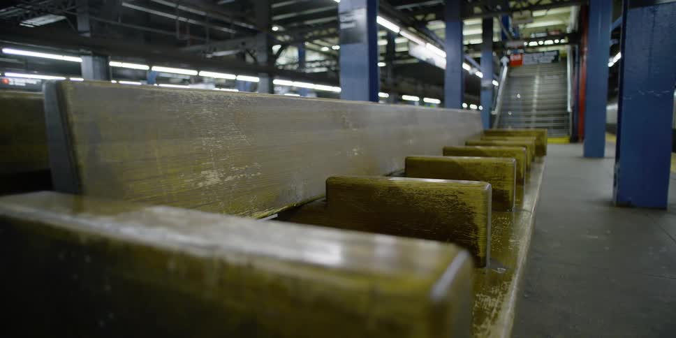 Wood benches fill the space below a staircase in a train terminal