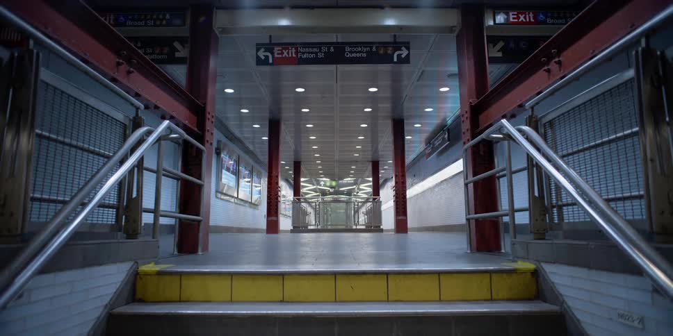 A subway staircase with signs and lights in the background