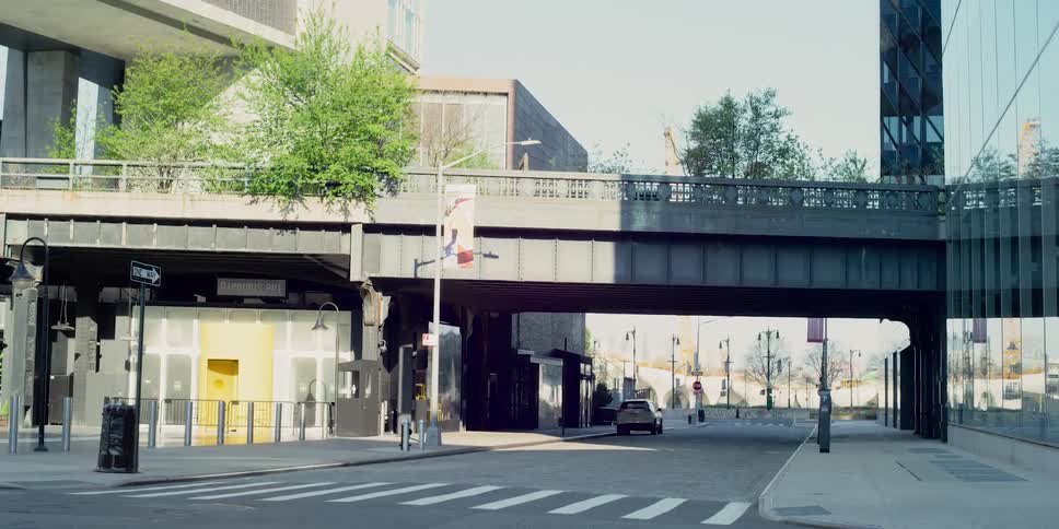Car parks on empty street near bridge passing between buildings