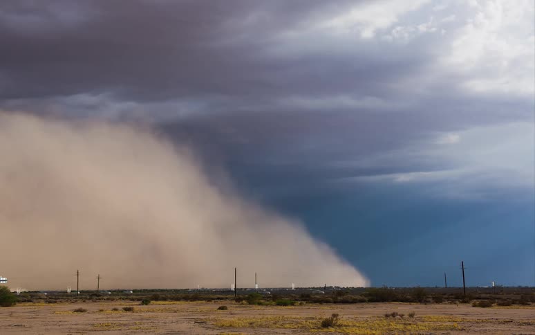 A dust storm rolls up and over a busy road