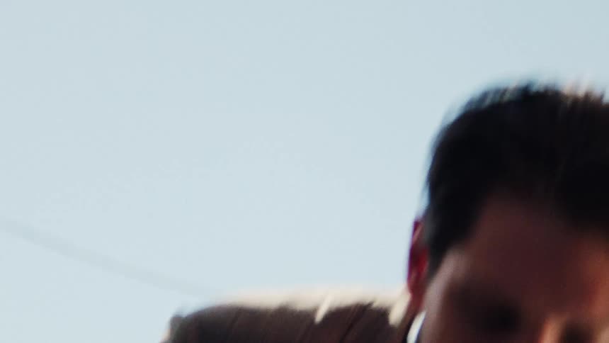 The view is of a young man walking outdoors in the middle of the day