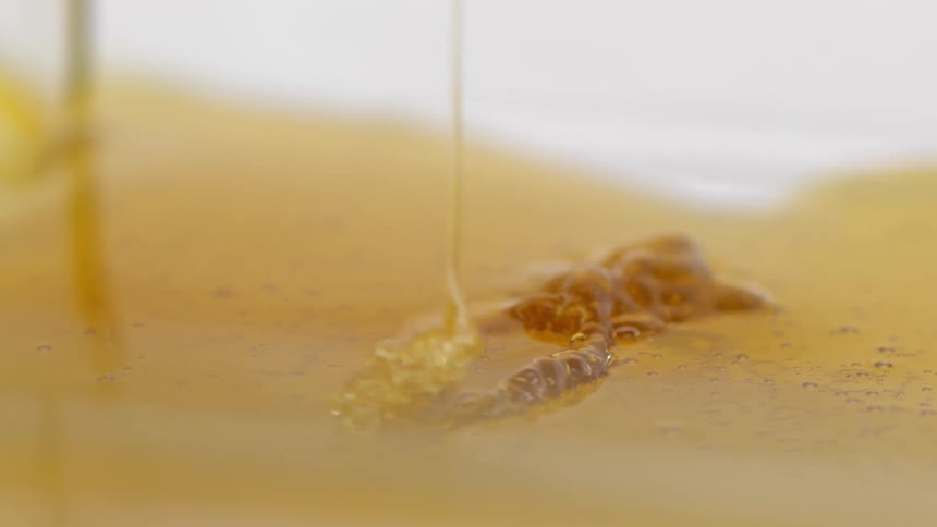 A goopy amber colored liquid drips and melts into a puddle