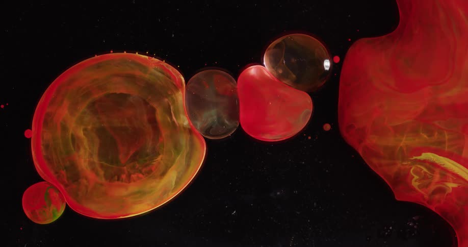 Internal rings expand in one of several bubbles abutting against each other on black background near red and yellow mass