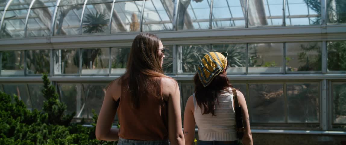 Two women walk toward a greenhouse