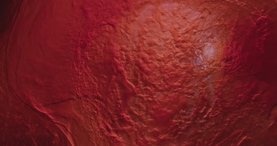 Reflective liquid flows over textured red surface leaving it dry