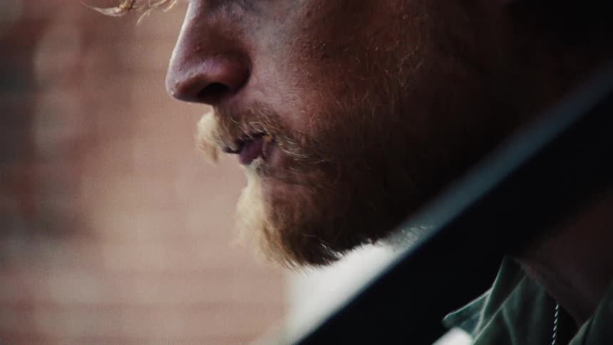 A close up of a man with a beard eating someone aggressively