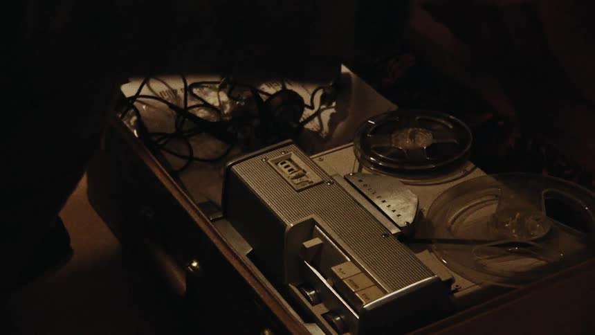 Two hands open an old suitcase to reveal old recording equipment inside