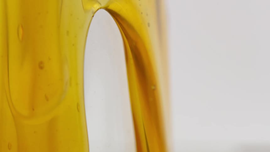 Close up of yellow clear honey flowing down a white wall
