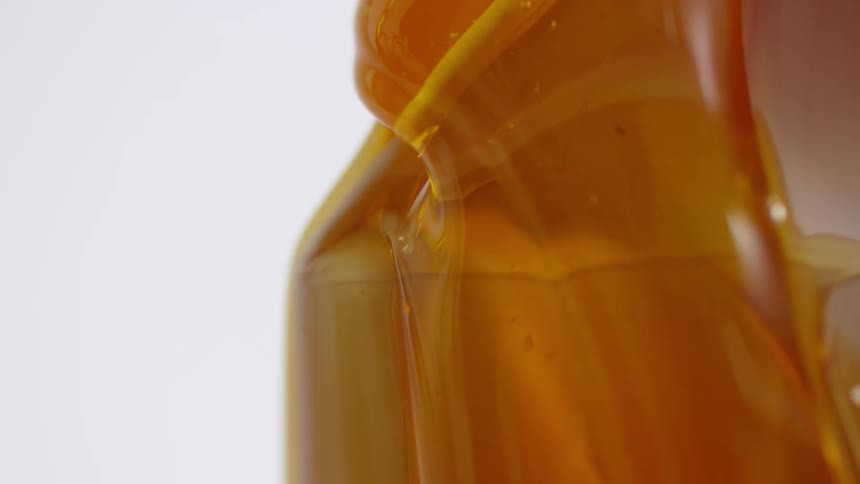 Amber honey flows downward to coat cardboard box