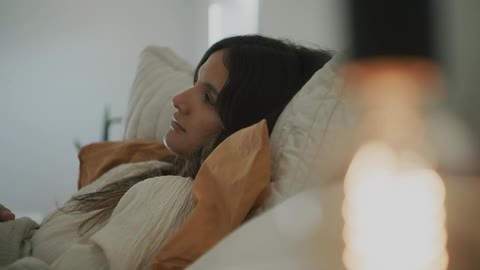 A woman is lying on the couch on a pillow as she turns her head and looks to her side
