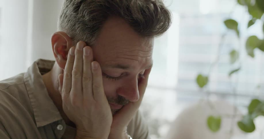 Man adding up numbers on notebook drops pencil and puts head on hands