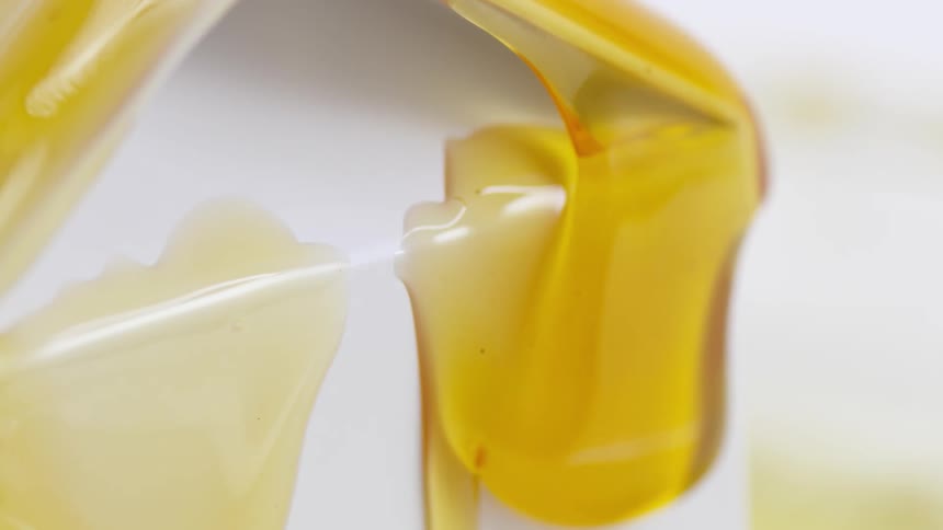 Honey slowly dripping down the side of a white box