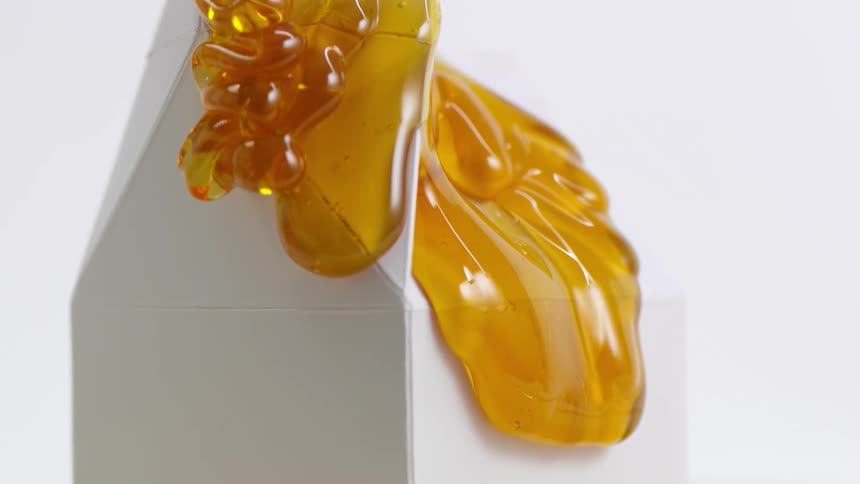 Amber syrup flows down white carton