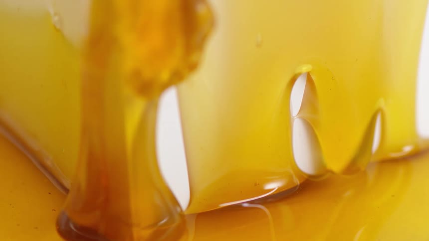 Amber syrup runs down to cover carton and surface