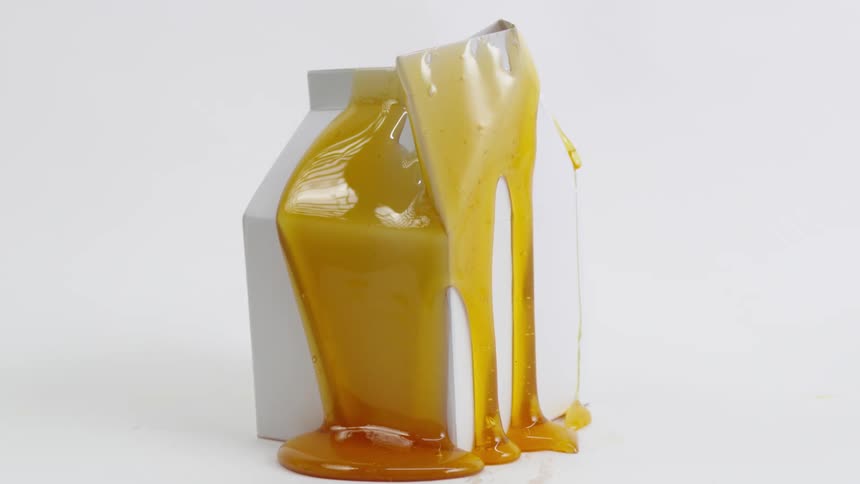 Honey oozing down the sides of a white milkbox shaped surface