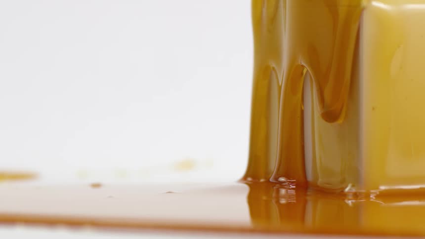 Honey oozing down a cubic block onto an already existing puddle of honey