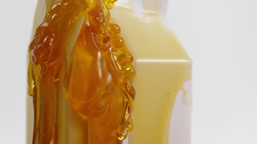 A goopy amber colored liquid flows and drips down the side of a container