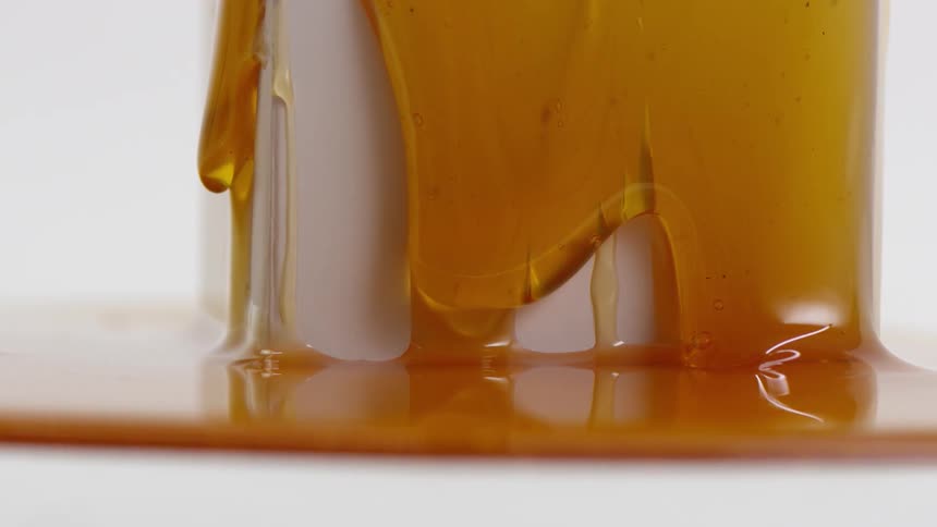 Honey oozing down a white block from all sides onto an already existing honey puddle