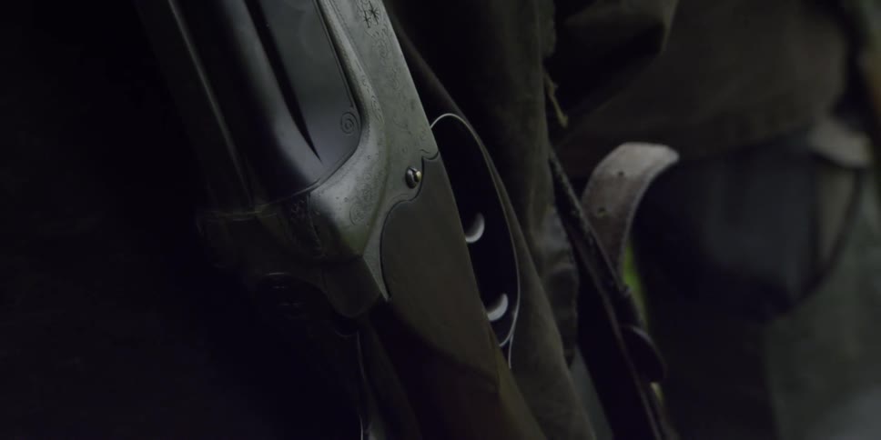 A person has a rifle hanging from his shoulder