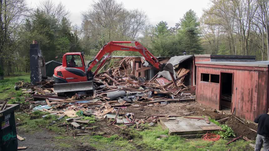 A row of houses are destroyed by an excavator