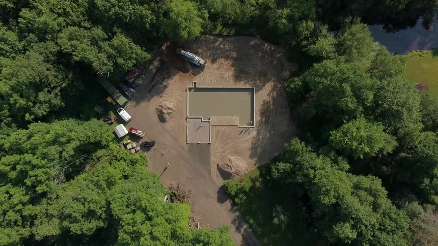 The foundation of a home that is being built in a heavily wooded area