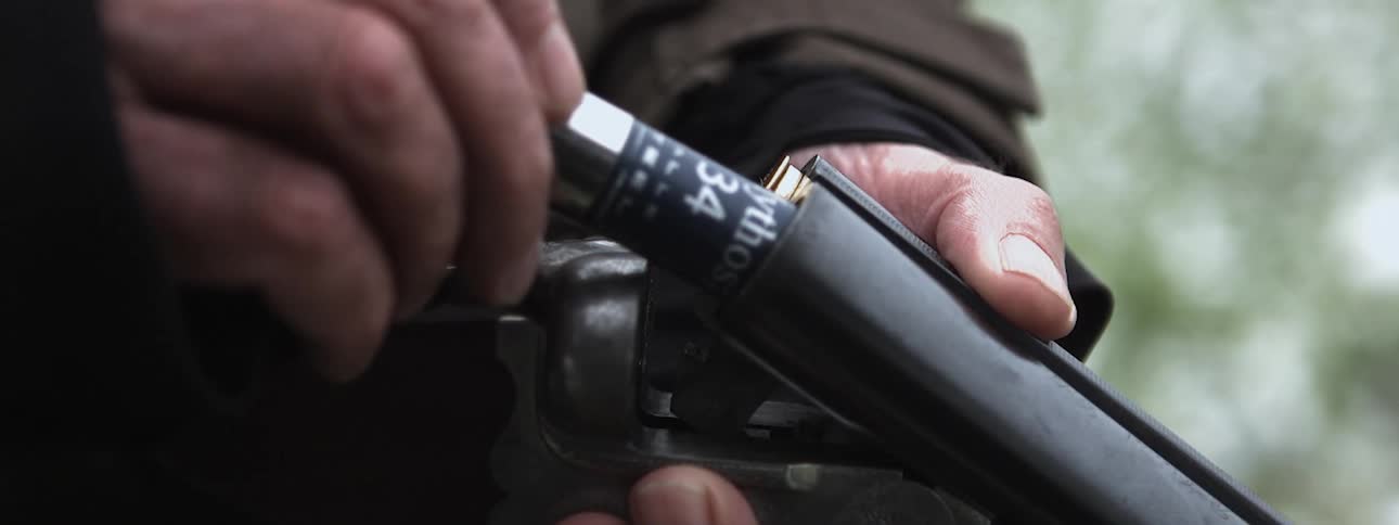 A person is loading their shotgun