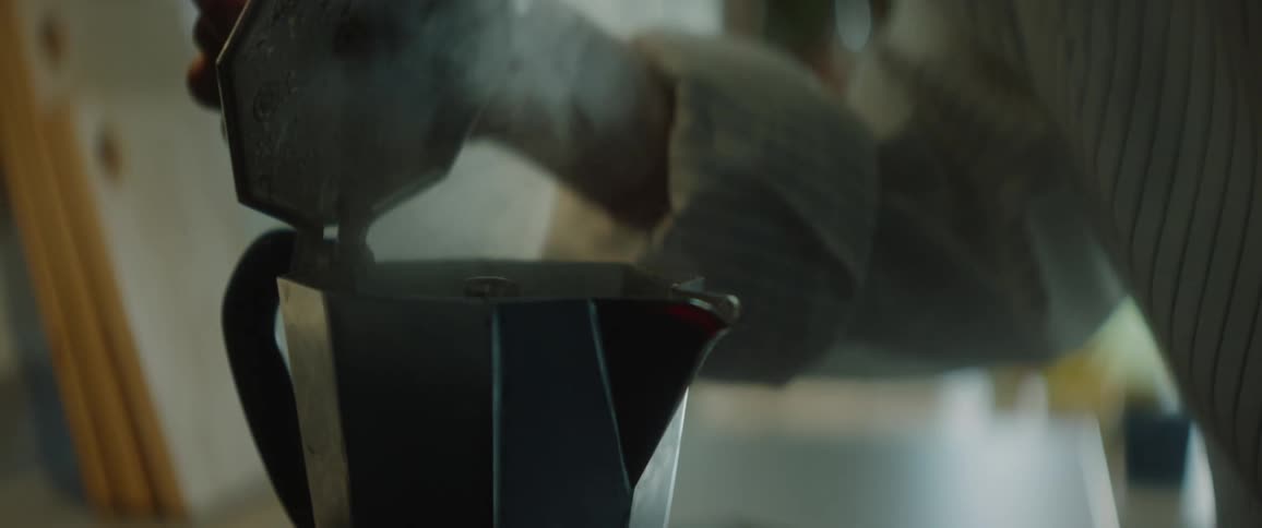 Woman in white shirt uses moka pot to make coffee