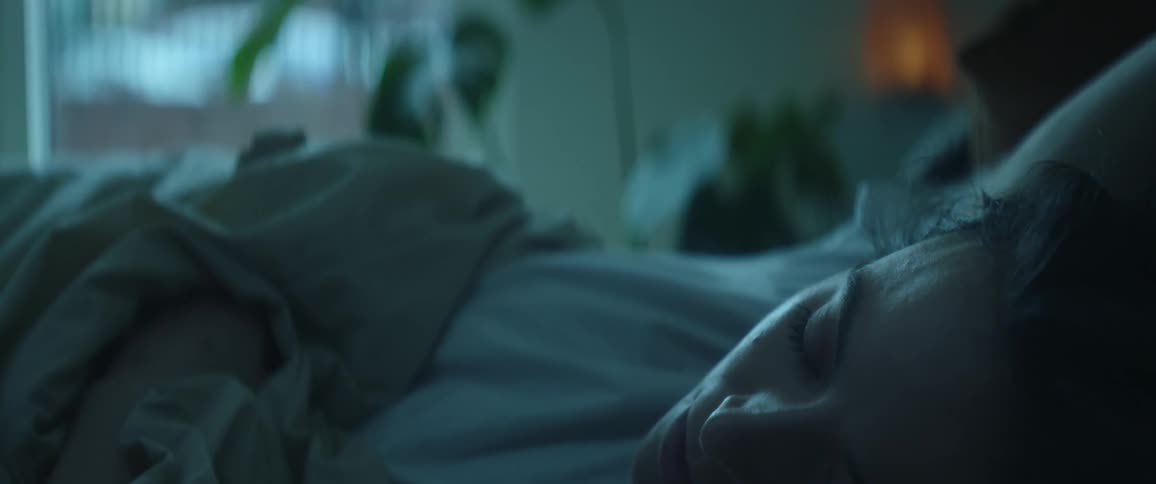 The view is of a young woman that is laying down in her bed