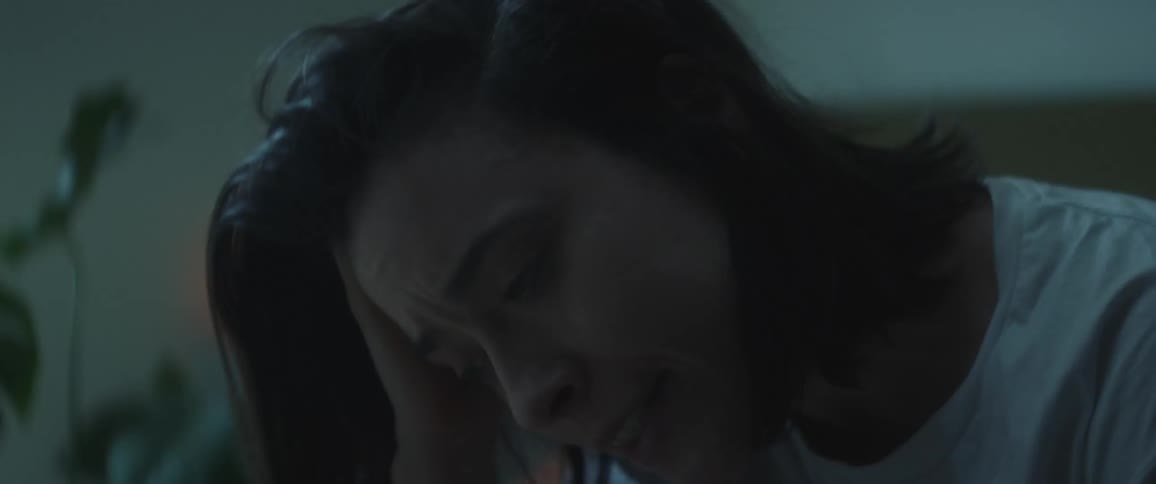 A close up of a womans face as she yawns and runs her fingers through her hair