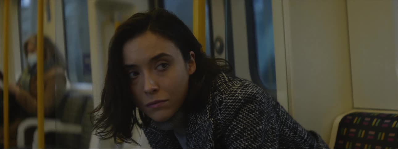 A woman is sitting on a train as it travels through the subway