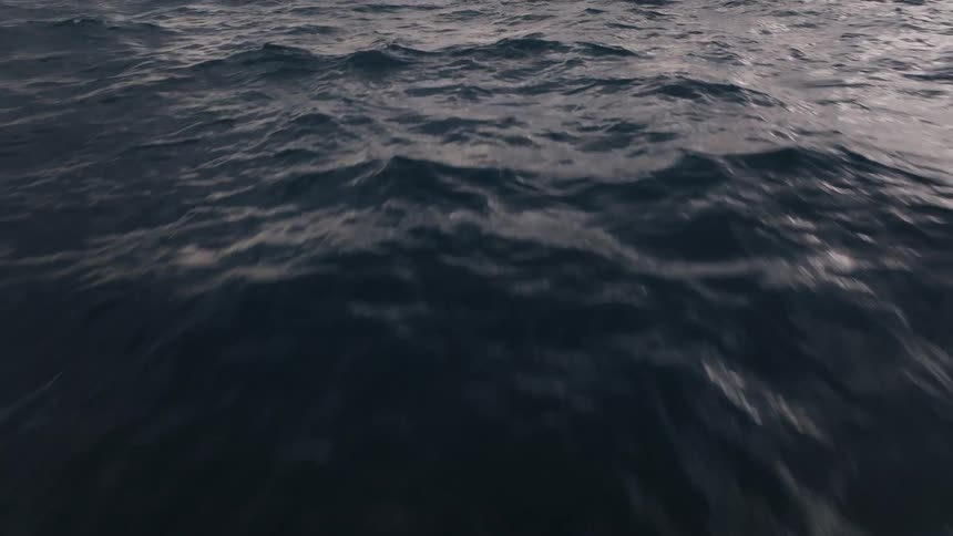 An aerial of the ocean with waves rolling across the surface