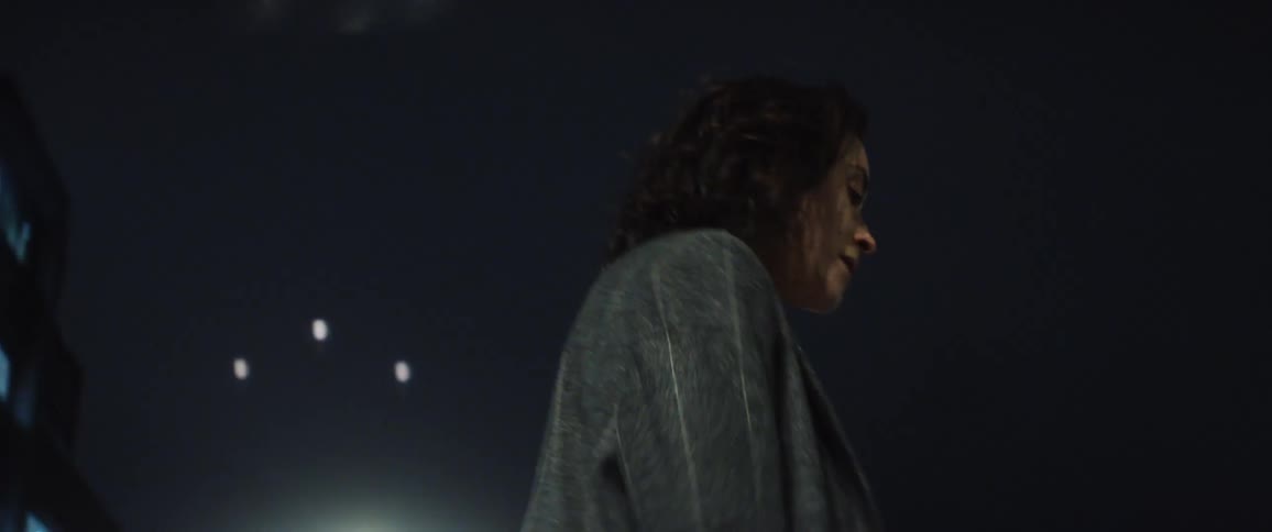 A young woman is dancing outside at night time