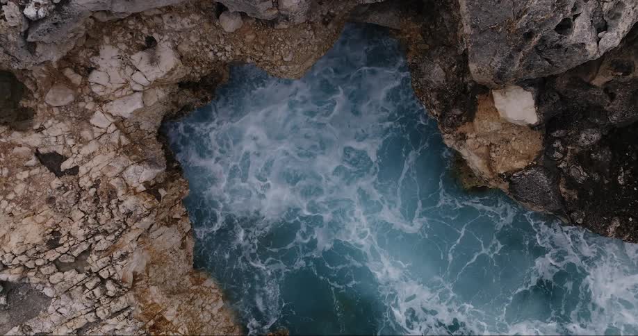 Foamy ocean waves breaking against the cliffside