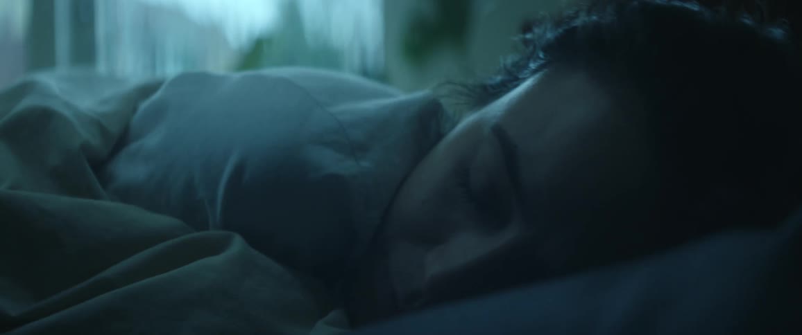 Woman sleeping in bed shifts and snuggles into pillow