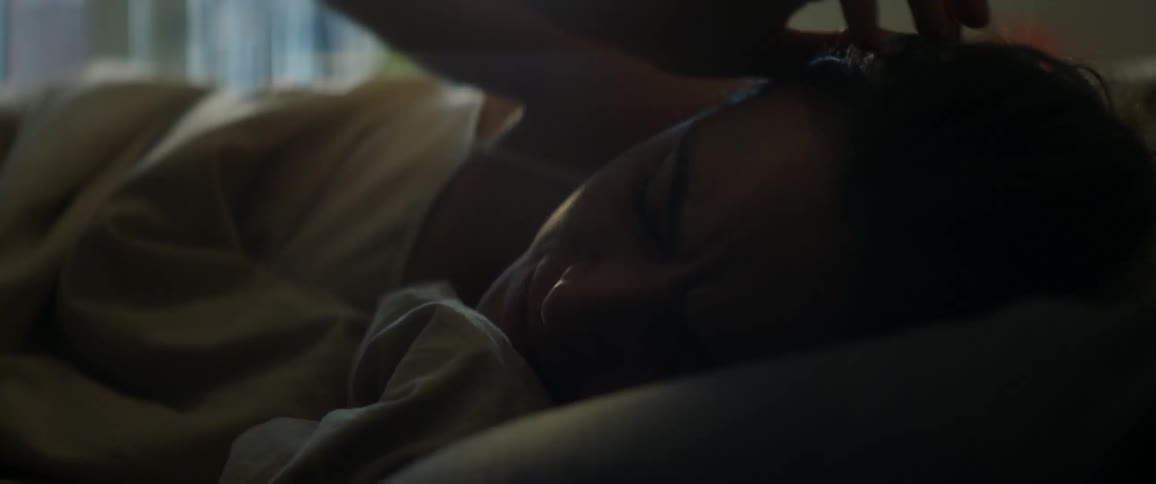 Woman rubs her eyes while waking in bed